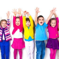 large group of children happily pulled his hands up in  white wall